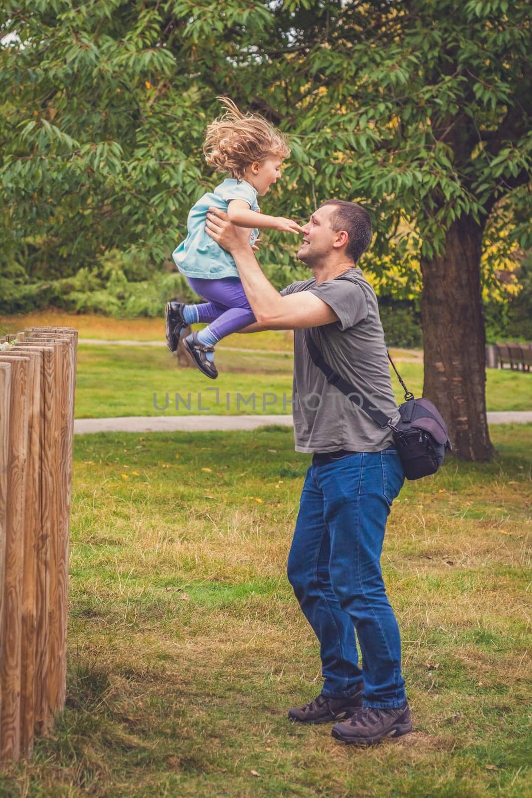 Father catching her daughter jumping from high wooden poles
