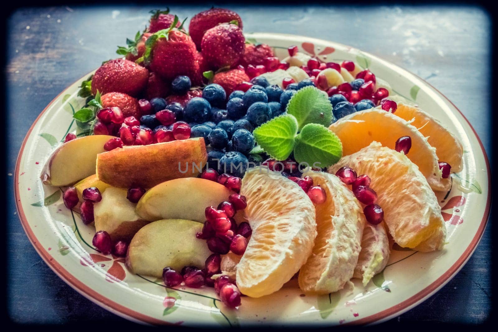 A closeup view of a platter of mixed fruits including strawberries, oranges, blueberries, apples and bananas