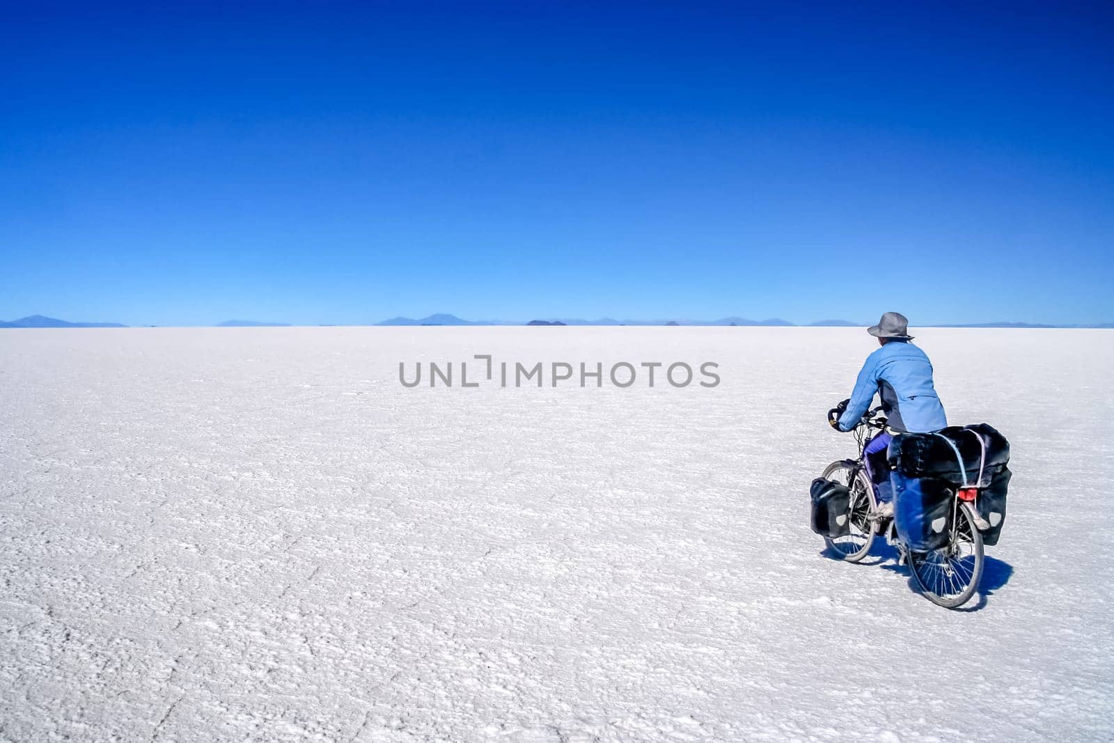 Lonely female cyclist travelling solo through the Salar de Uyuni in Bolivia, the biggest salar in the world