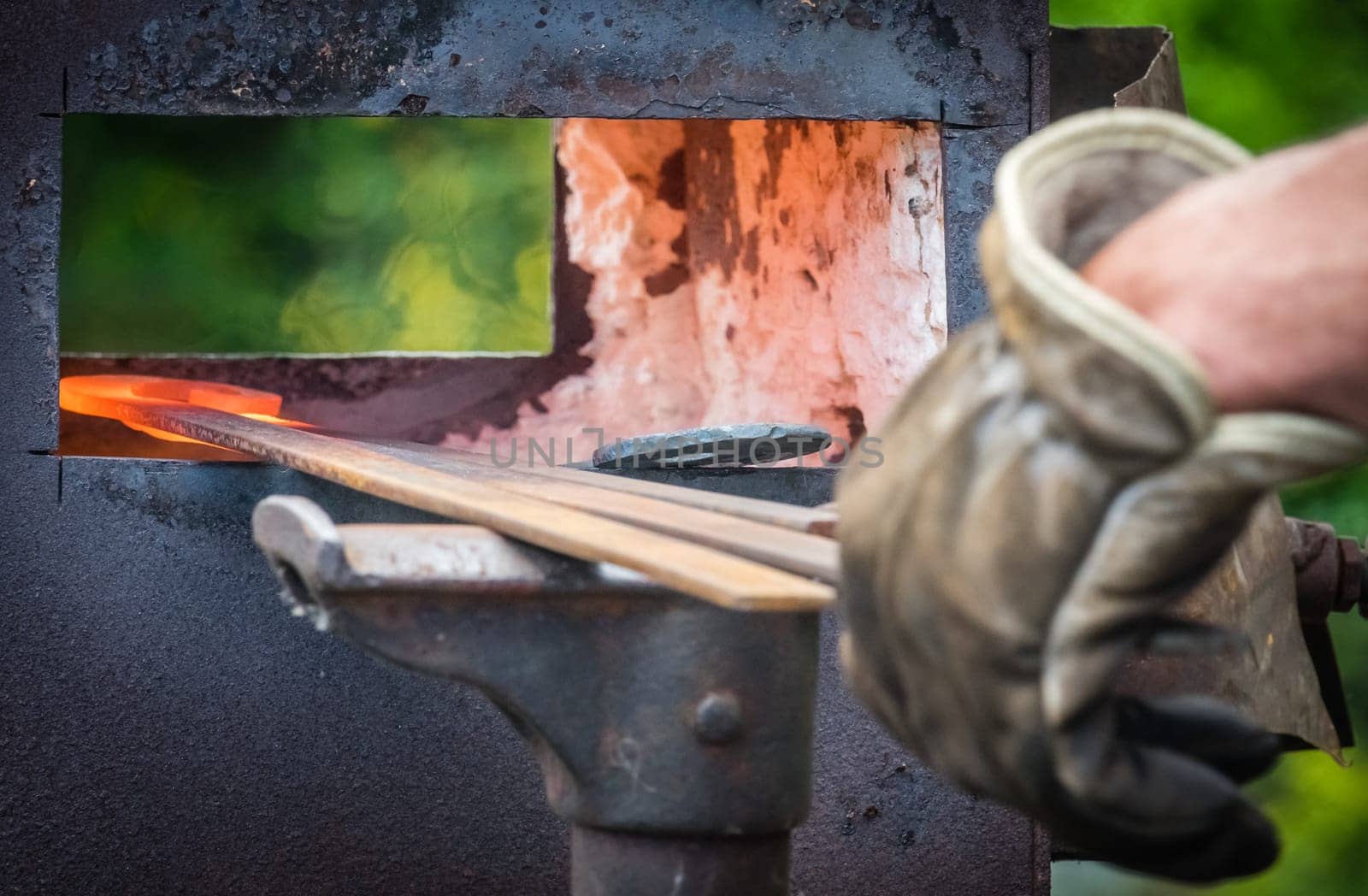 A blacksmith inserting steel rods into the hot oven  during medieval fair festival in Streatham Park in London