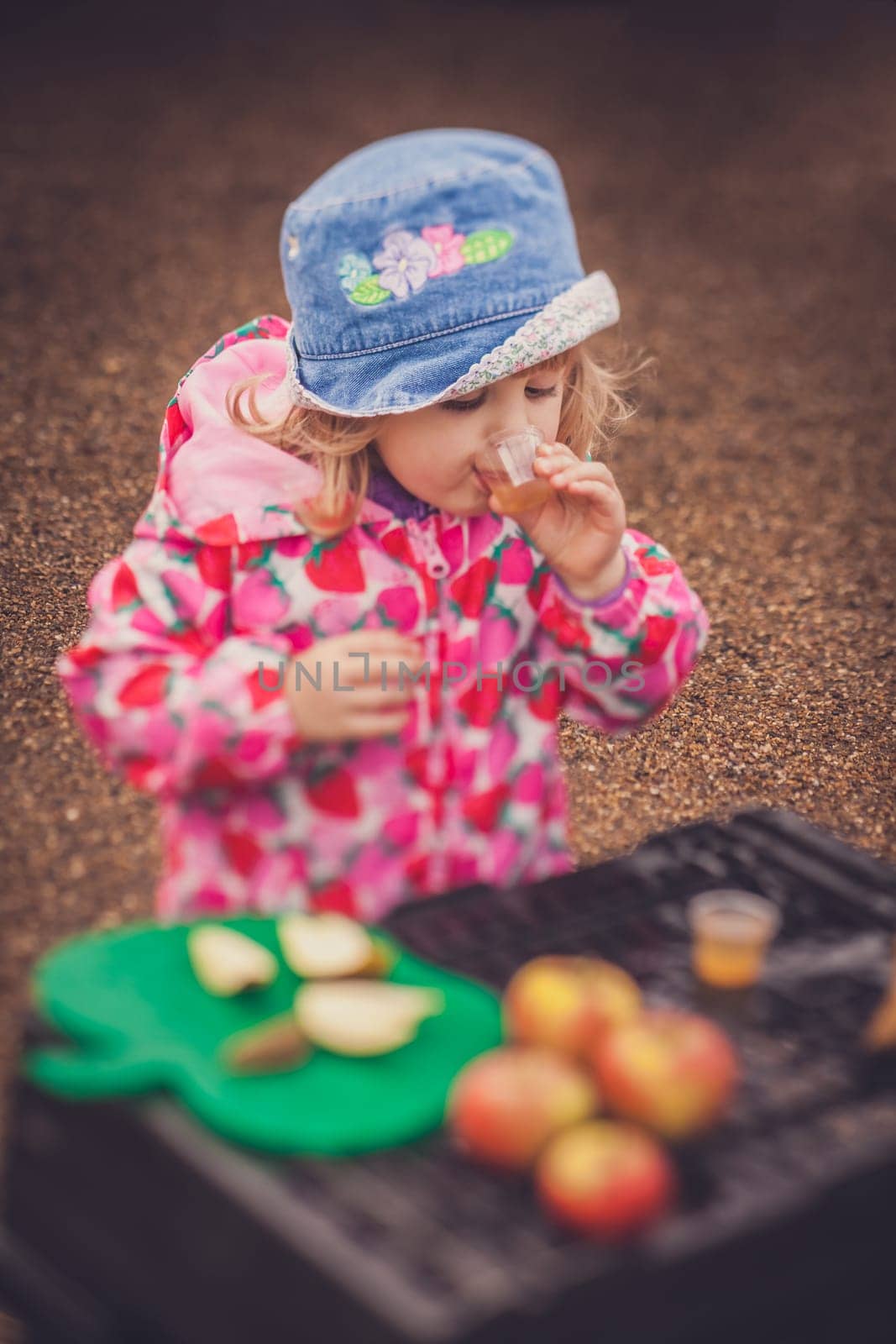 Portrait of a cute little girl tasting fresh organic apple juice at a local farmers market