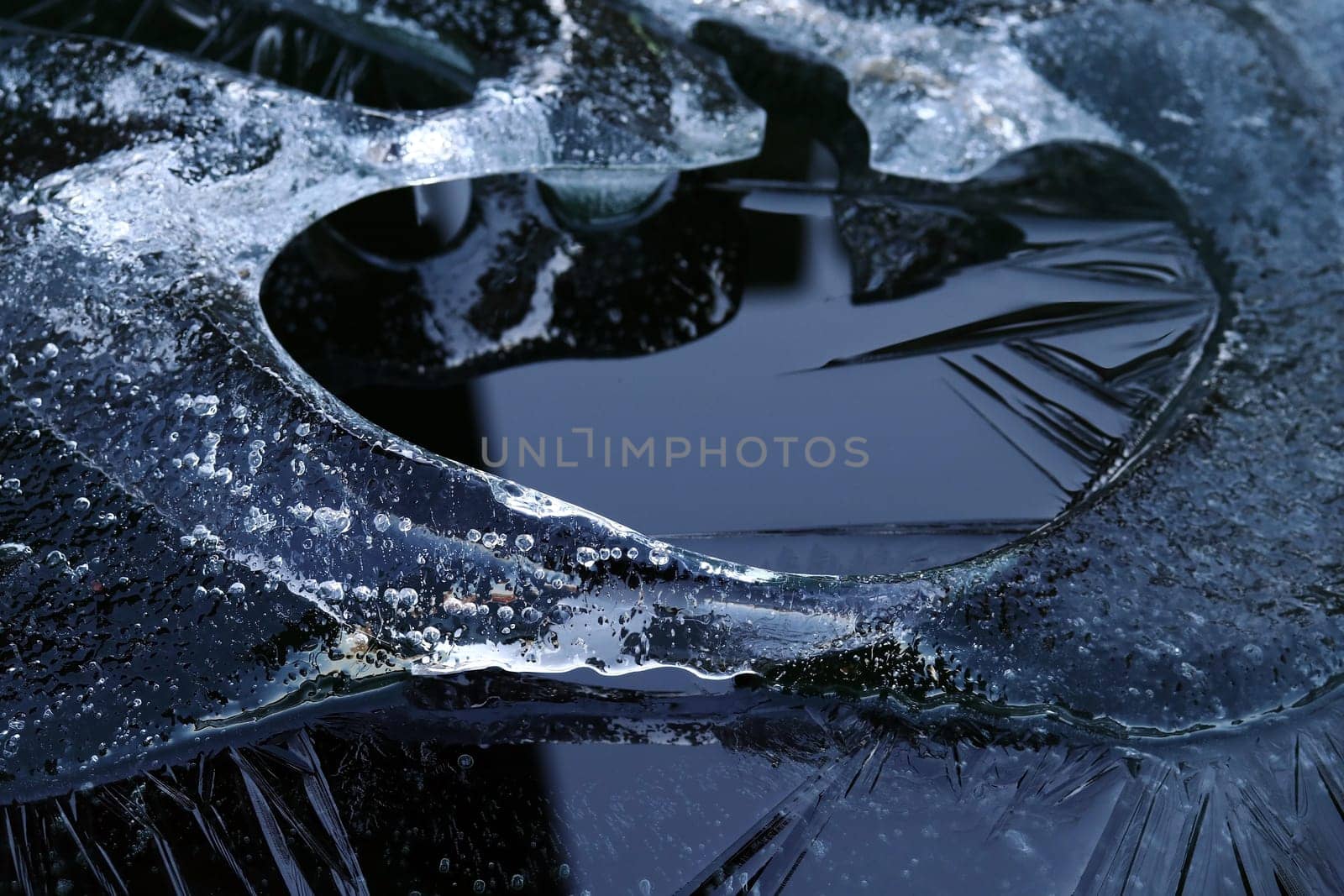 A chunk of ice with frozen air bubbles in the water. A small iceberg in the water