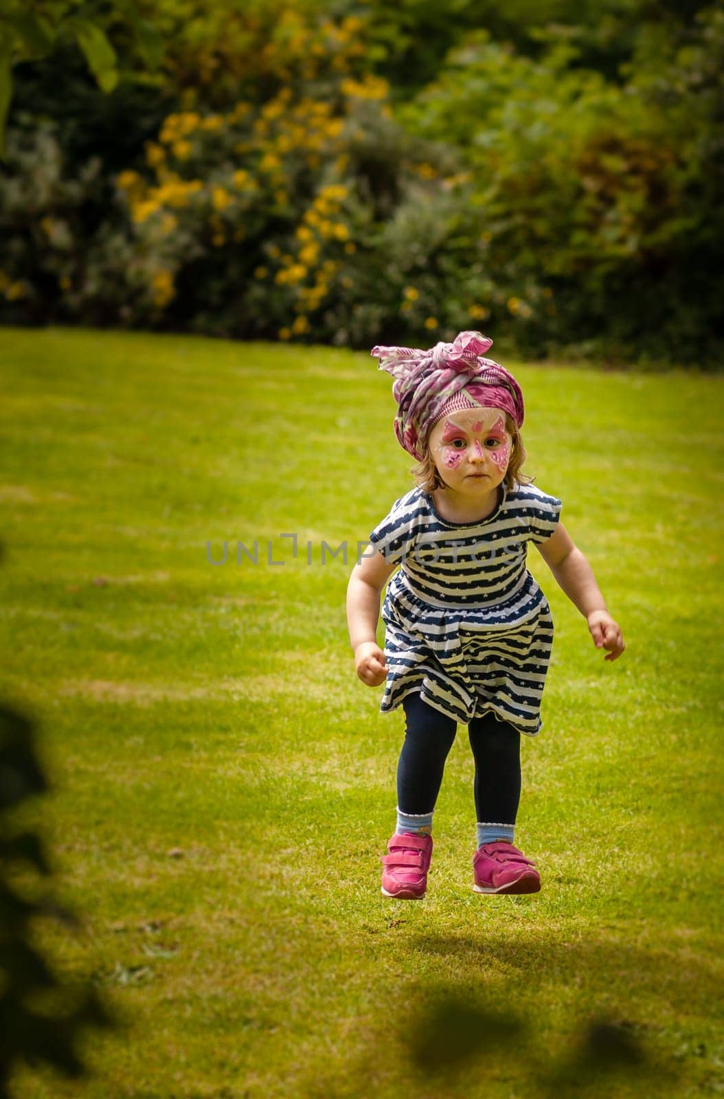 Cute little girl jumping high in a park in autumn