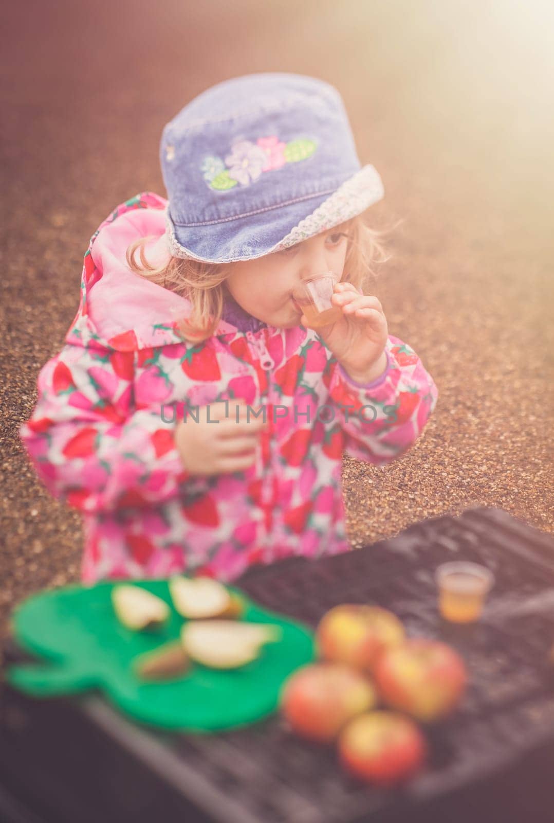 Portrait of a cute little girl tasting fresh organic apple juice at a local farmers market