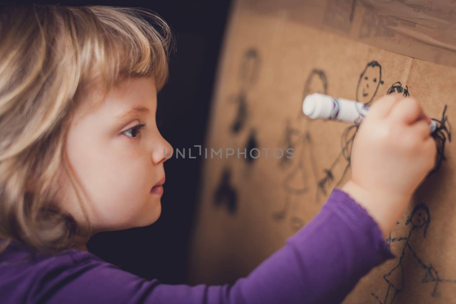 Little girl drawing on a cardboard at home