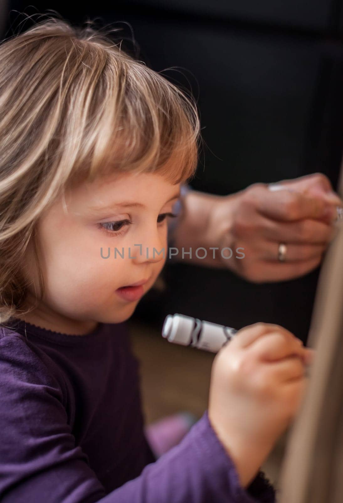 Little girl drawing on a cardboard at home