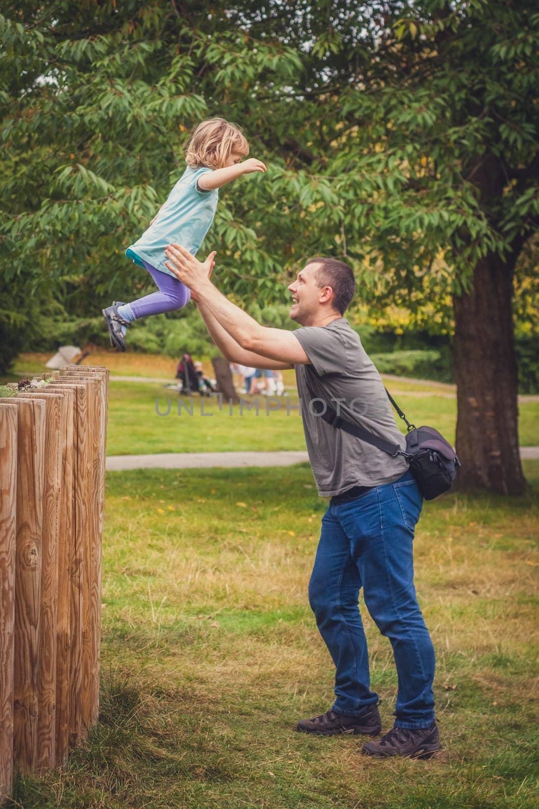 Father catching her daughter jumping from high wooden poles