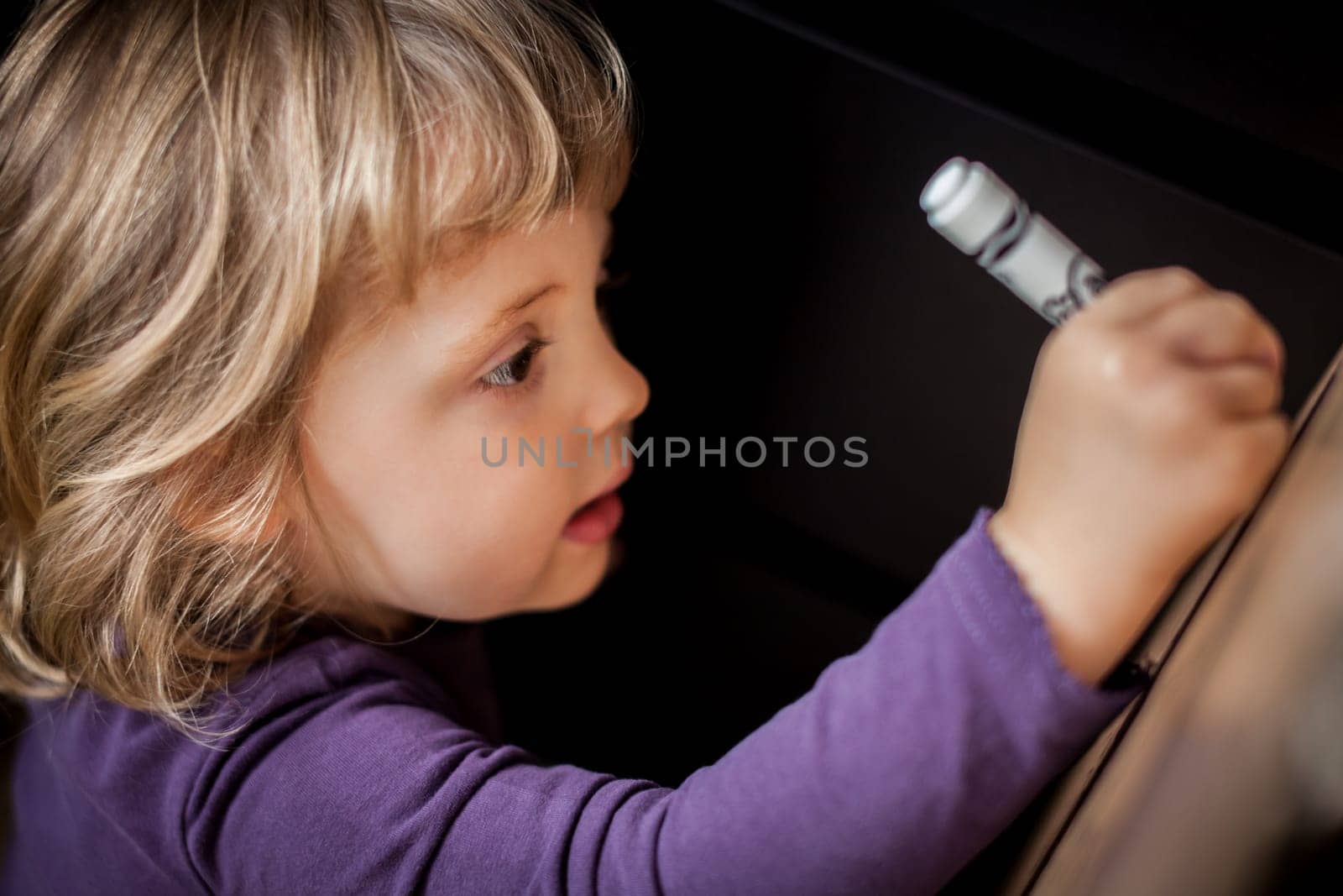 Little girl drawing on a cardboard at home