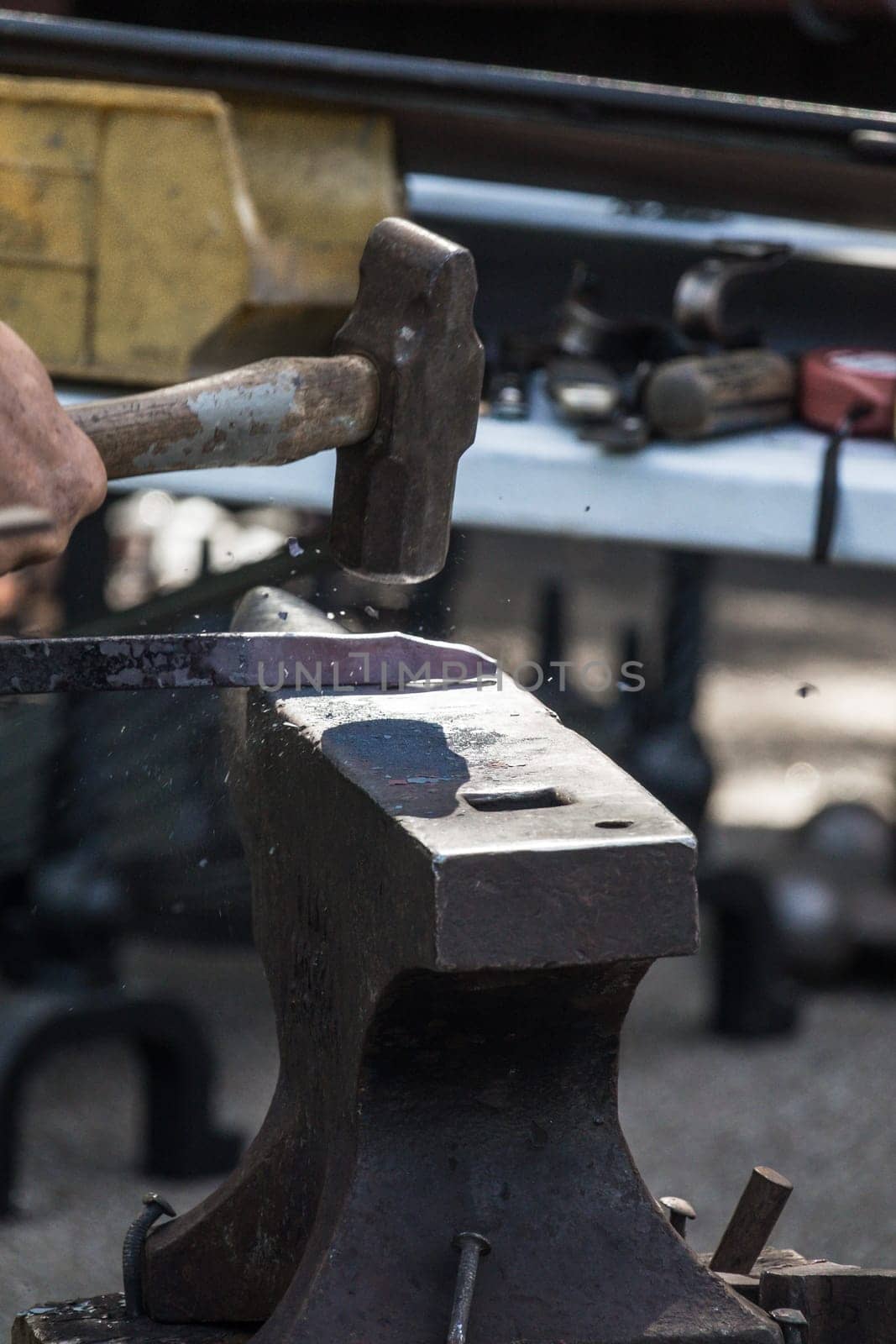 A blacksmith hammering hot iron during medieval fair festival in Streatham Park in London