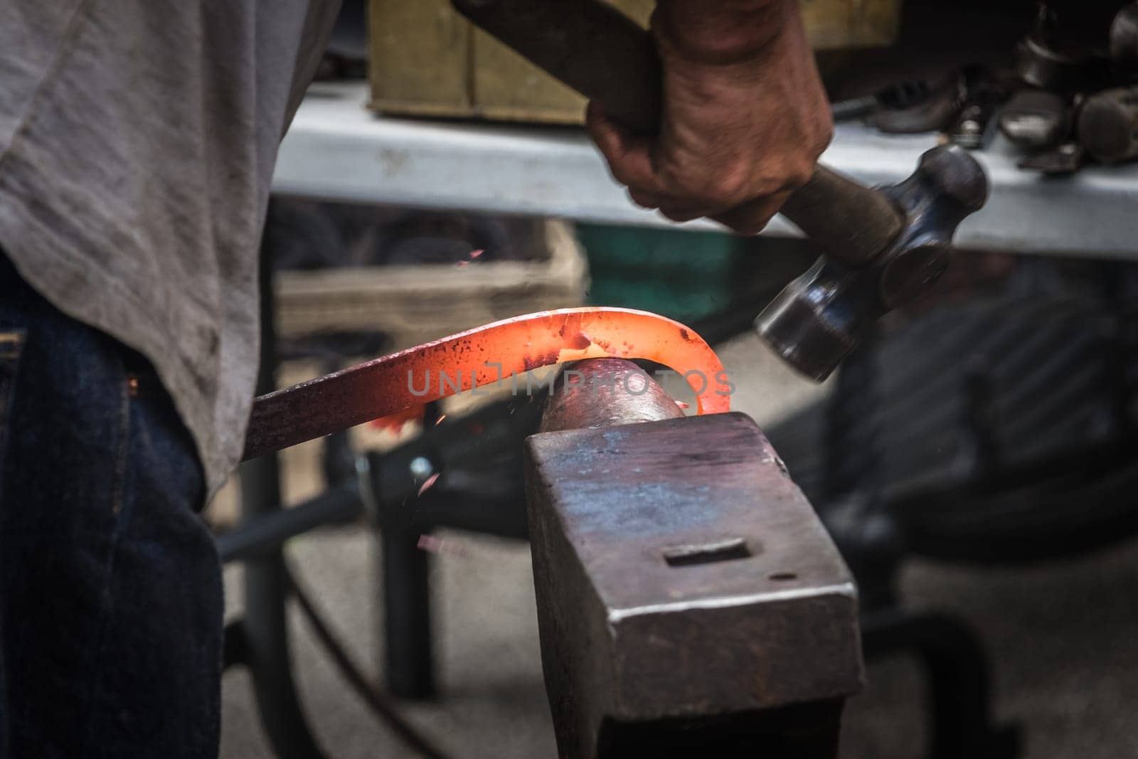 A blacksmith hammering hot iron during medieval fair festival in Streatham Park in London