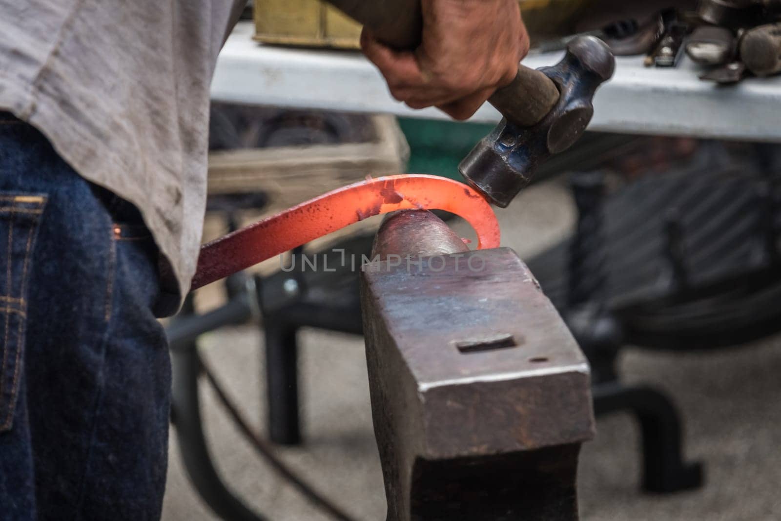 A blacksmith hammering hot iron during medieval fair festival in Streatham Park in London