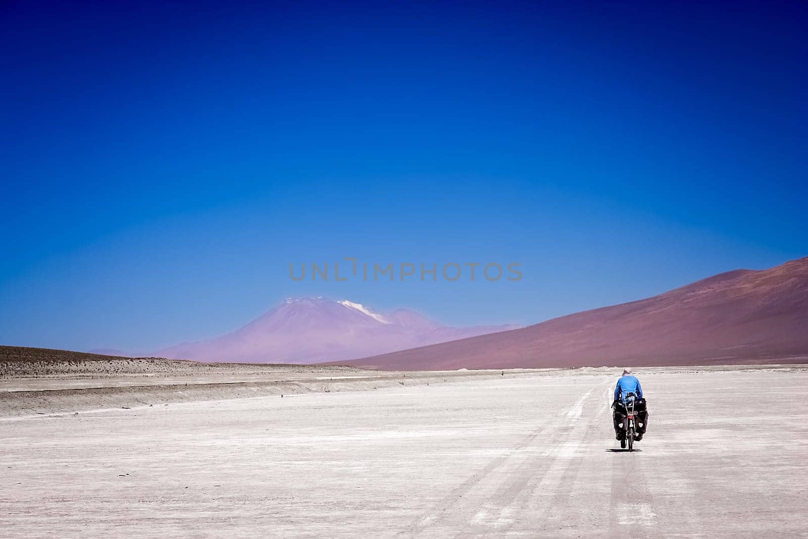 Lonely female cyclist travelling solo through the Salar de Uyuni in Bolivia, the biggest salar in the world