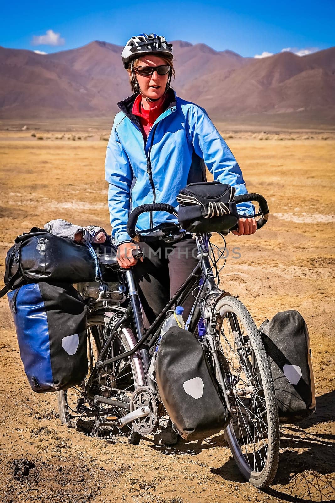 Female cyclist stuck in deep sand in the dry, desolate, empty rural countryside in central Bolivia