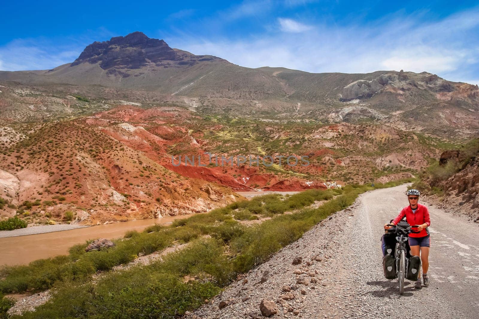 Woman pushing her bicycle uphill on a gravel stretch of the famous national Ruta 40 Quarenta in the remote part of central Argentina