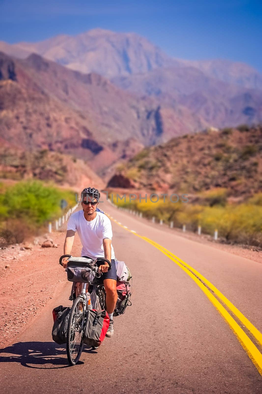 Man cycling on the empty road to Cafayate in the remote part of north west Argentina