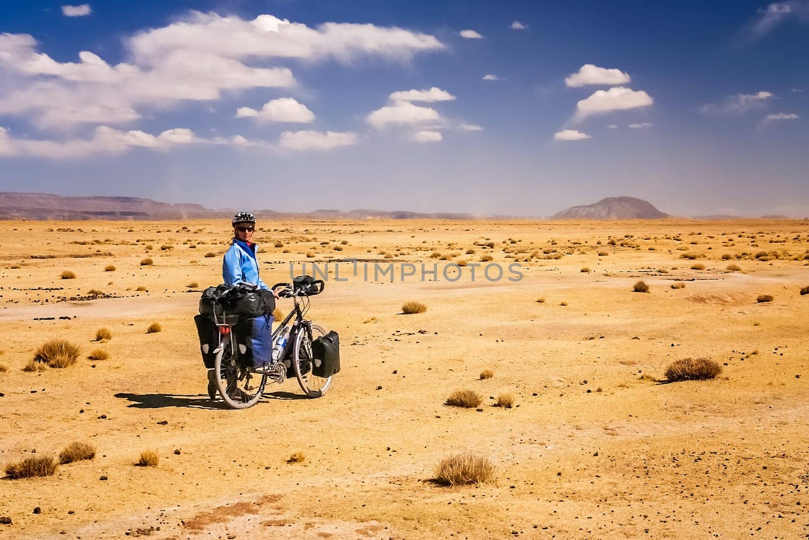 Woman cycling through the dry, desolate, empty countryside towards Oruro in central Bolivia