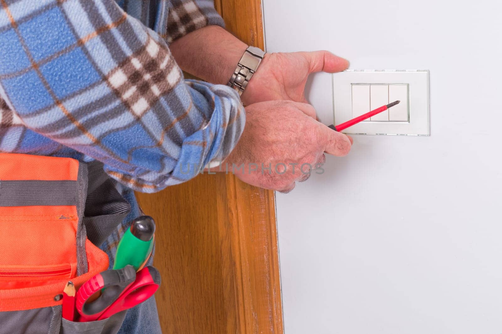 The technician wears the normal protective devices. Electrician's hands assembles a standard bipolar wall socket.