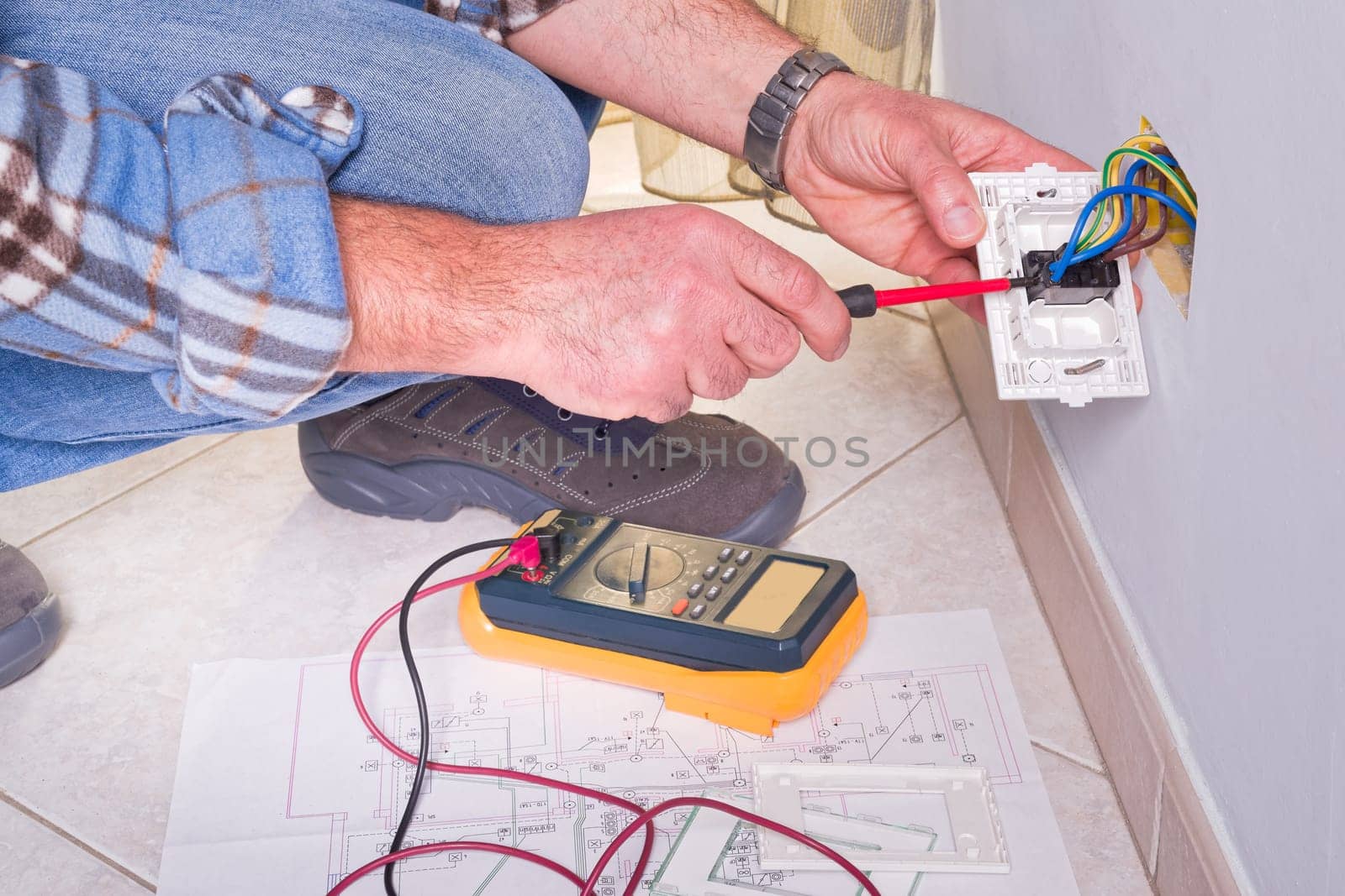 Electrician's hands assembles a standard bipolar wall socket.