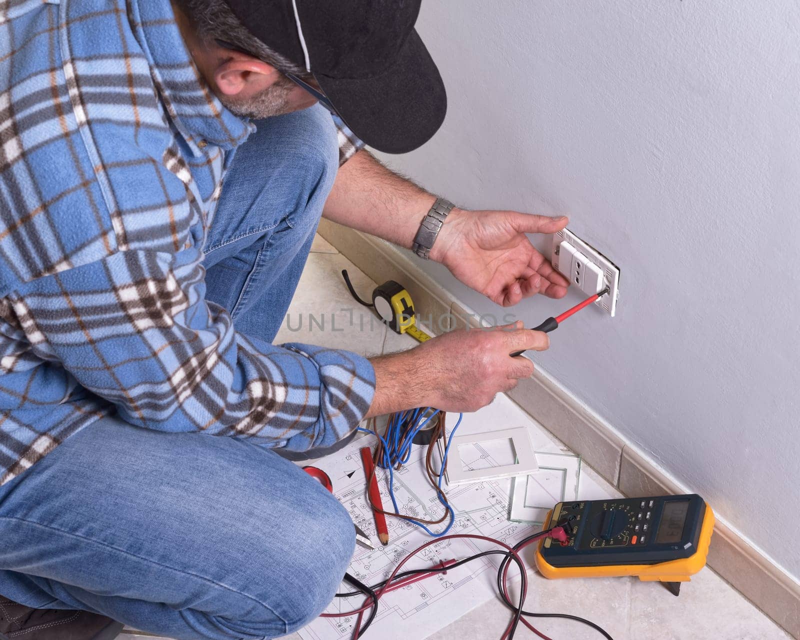 The technician wears the normal protective devices. Electrician's hands assembles a standard bipolar wall socket.