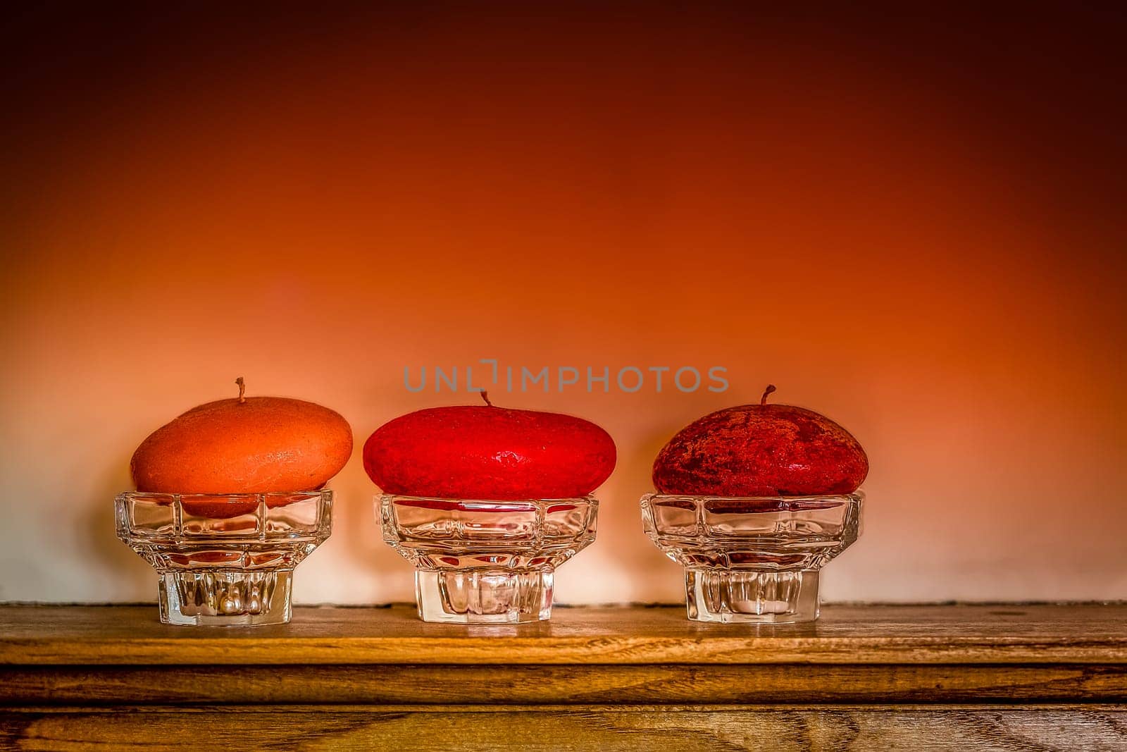 Three candles standing on a wooden panel above fireplace