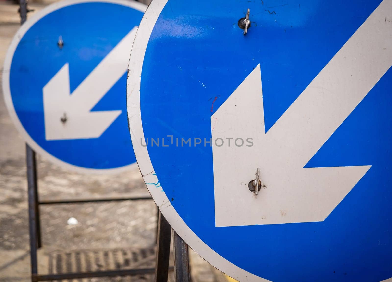 Two blue round road signs indicating on which on the lines you have to drive