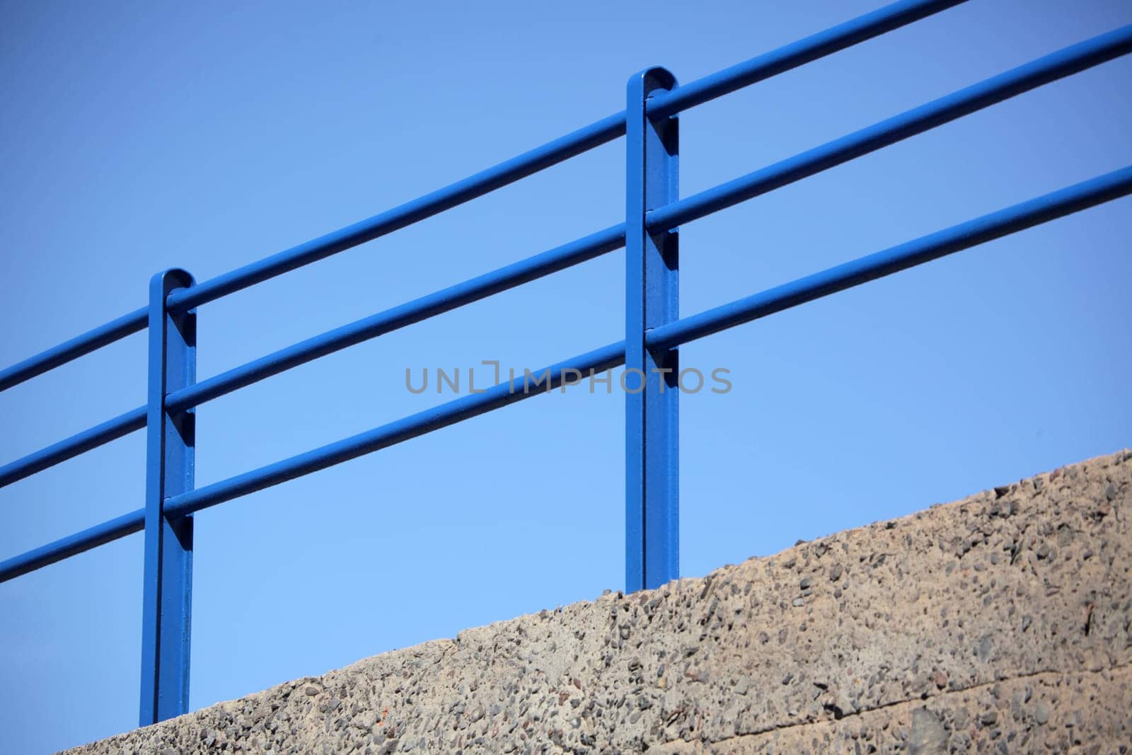 Blue steel railing with clear blue sky in the background