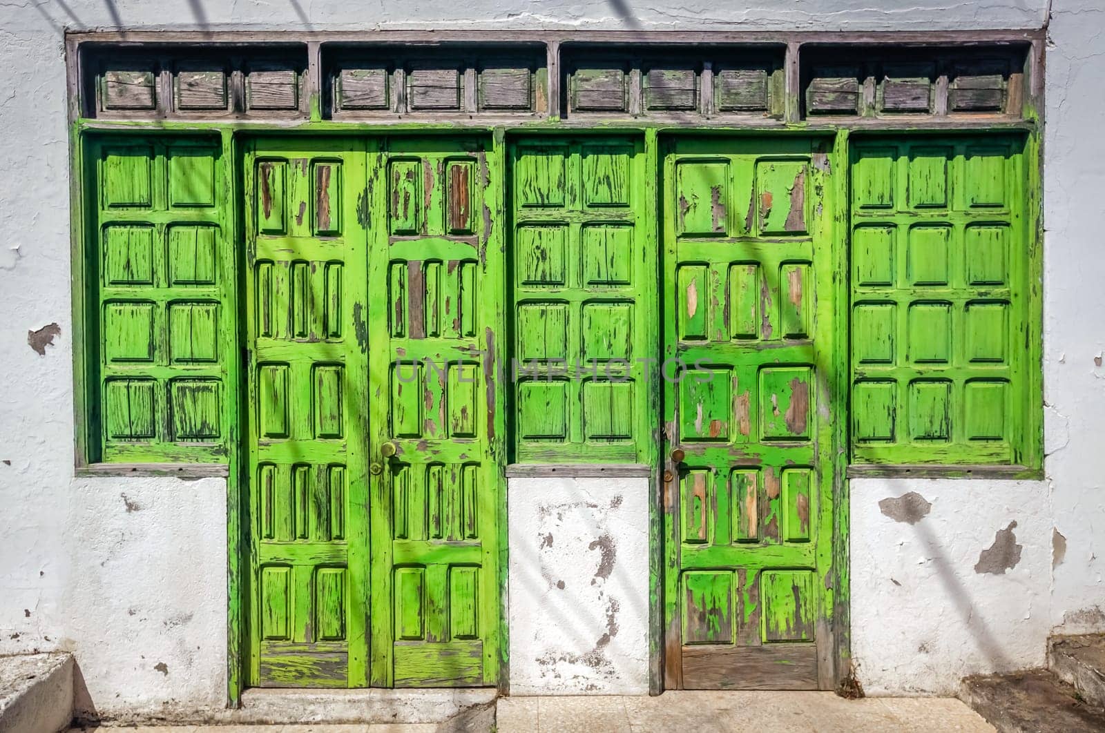 Old green damaged wooden doors in one of the colonial buildings in La Gomera island, Spain