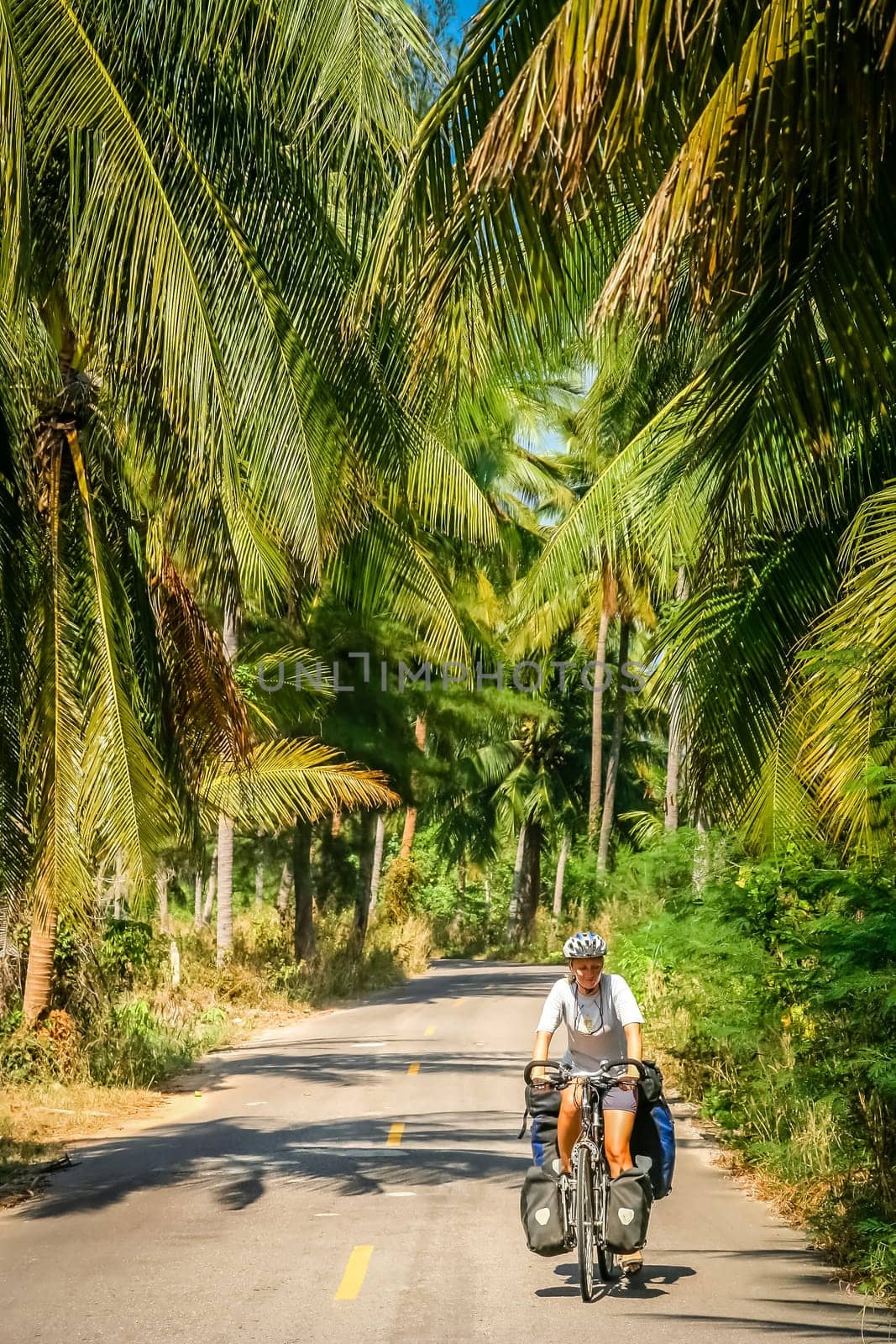 Female cyclist cycling through tropics in central Thailand