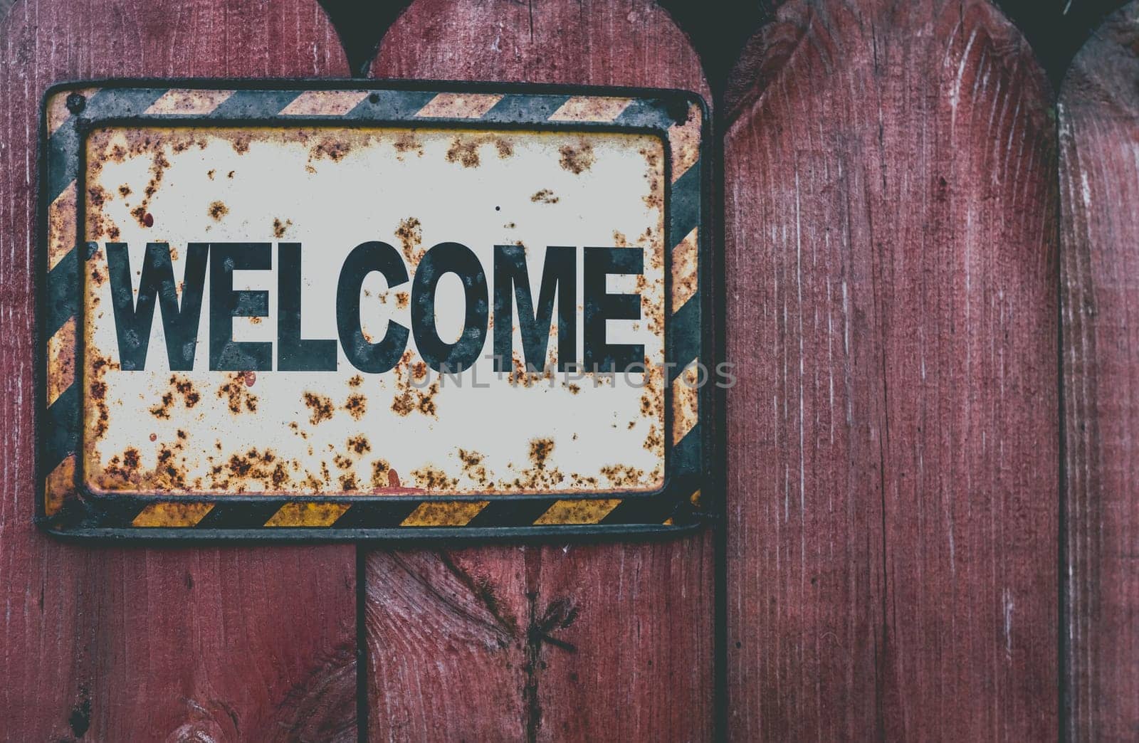 Welcome plaque on a grunge wooden fence background