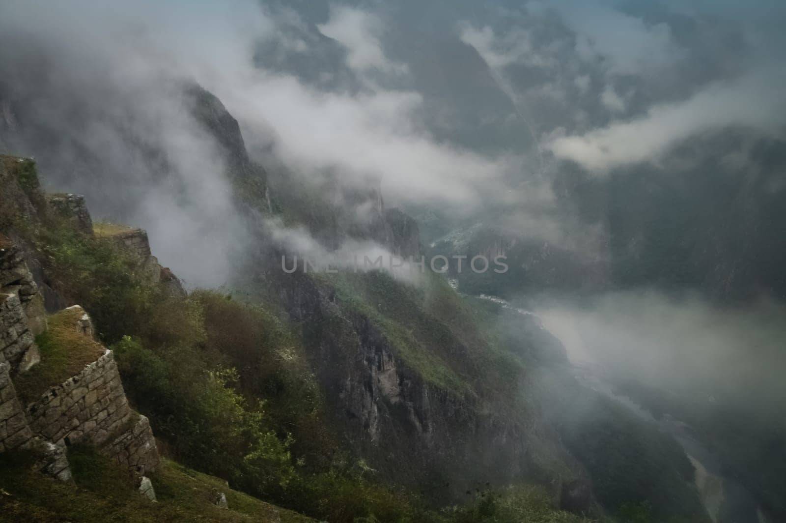 Ancient inca town of Machu Picchu covered in mist, fog and clouds in the morning, Peru