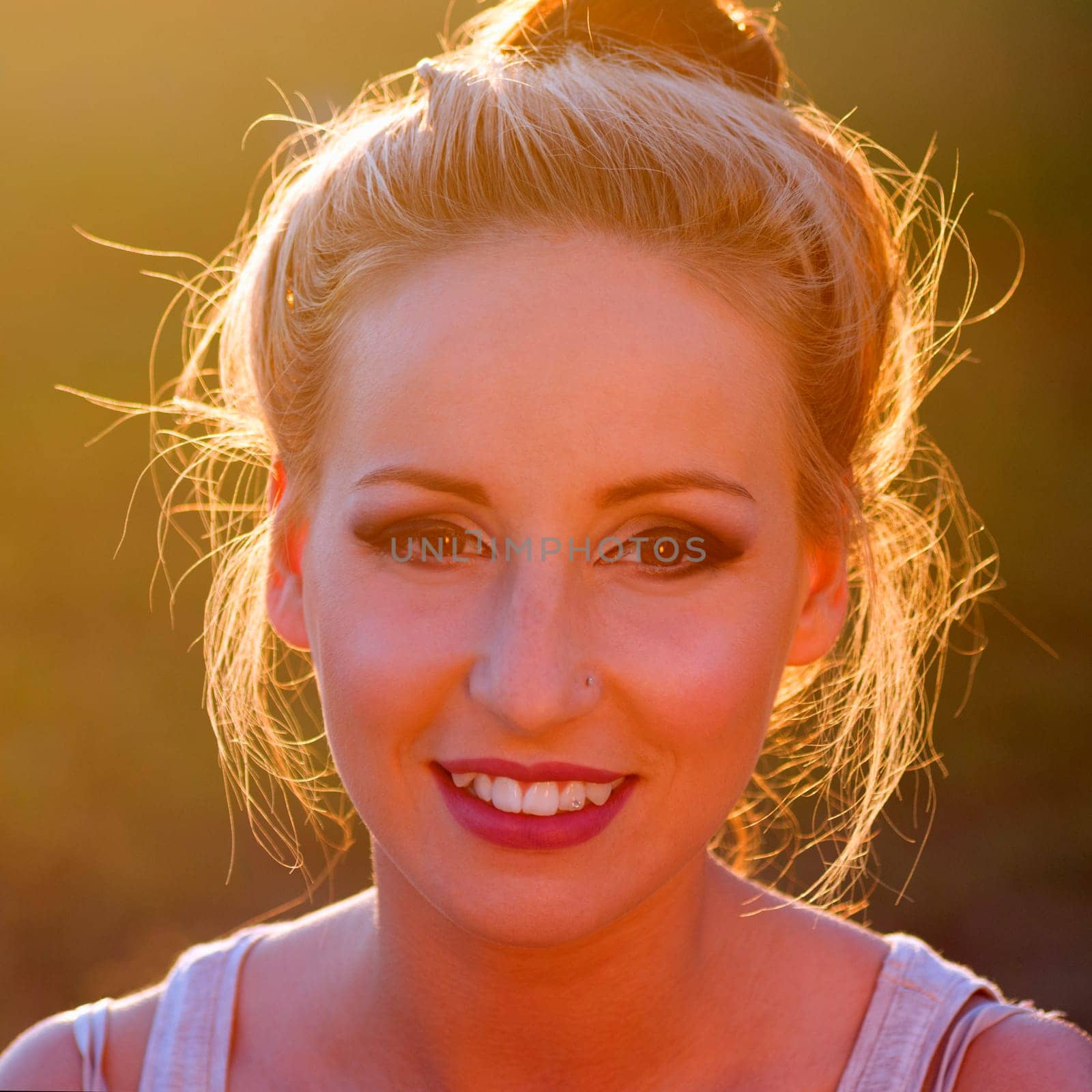 Portrait about a smiling young woman at sunset.