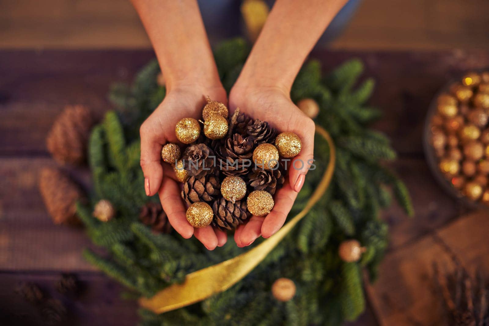 Close-up of female hands with fir-cones and golden balls