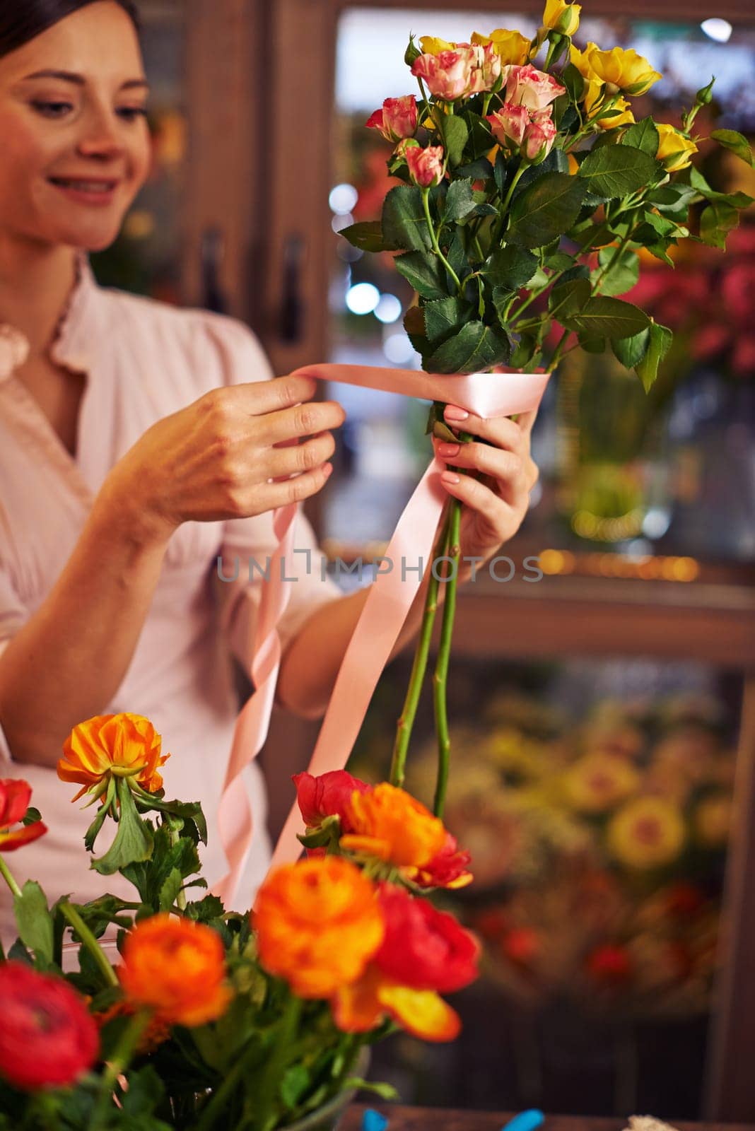 Young woman banding rose bouquet with a ribbon