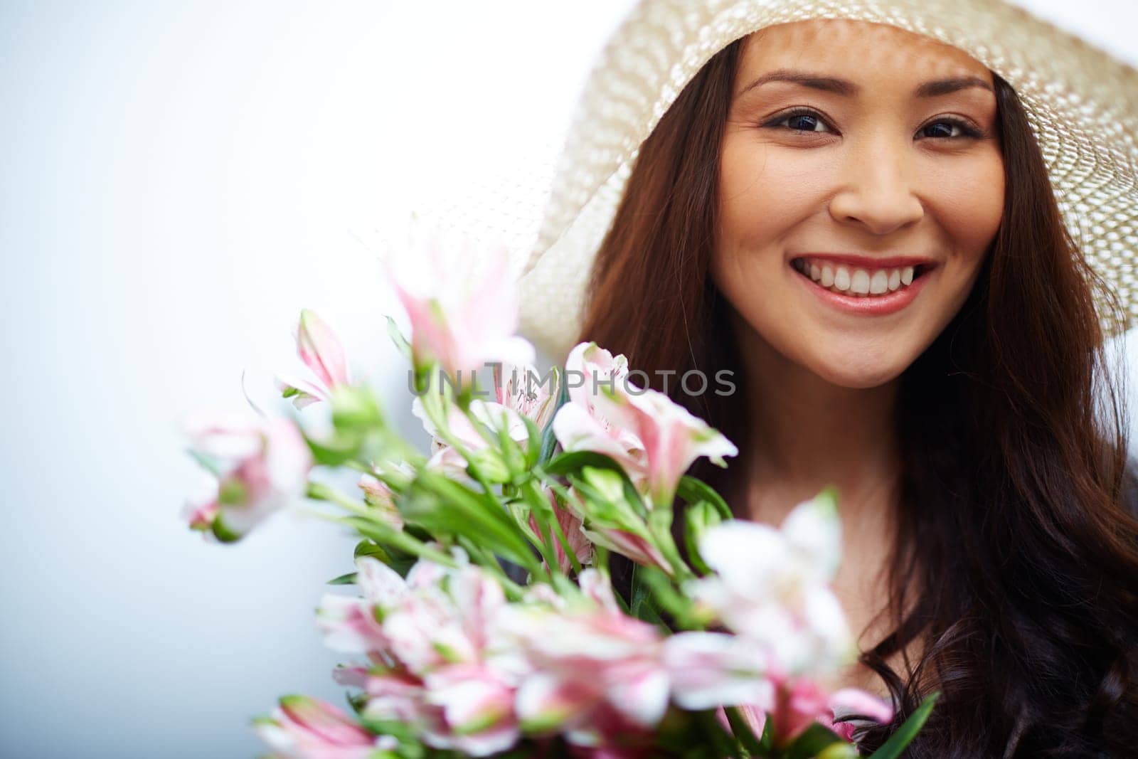 Elegant woman in hat looking at camera out of bunch of flowers