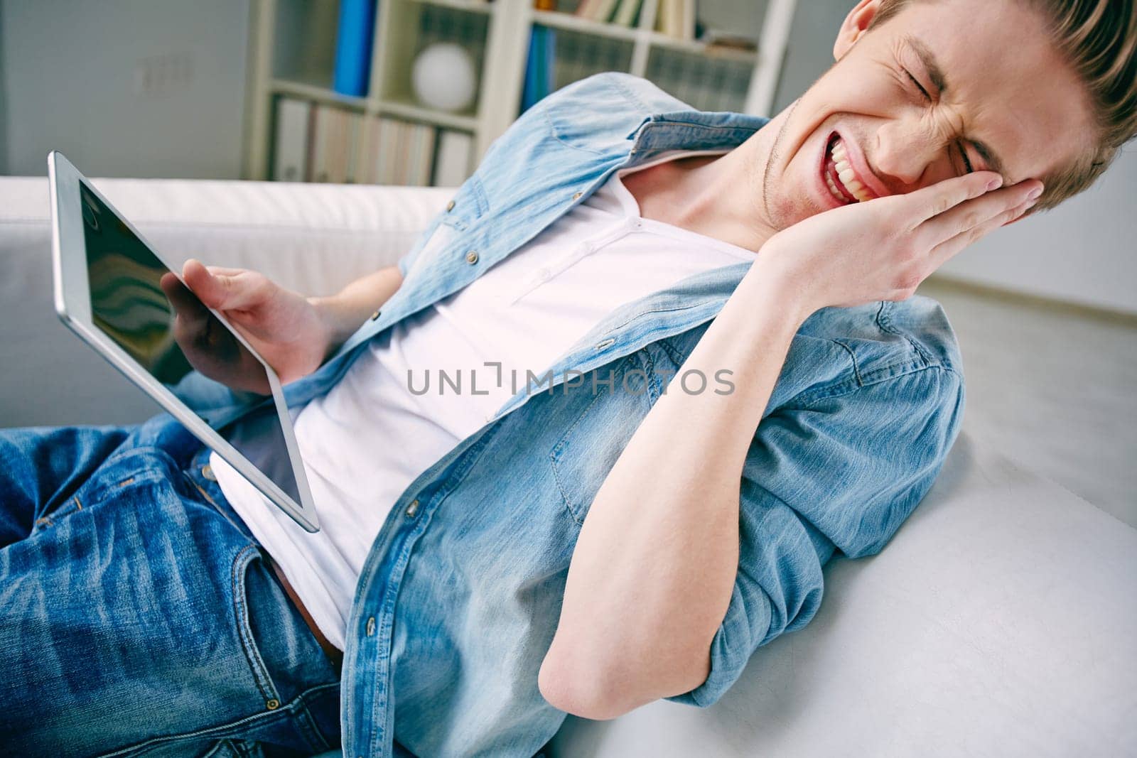 Young man laughing at his photo on touchpad