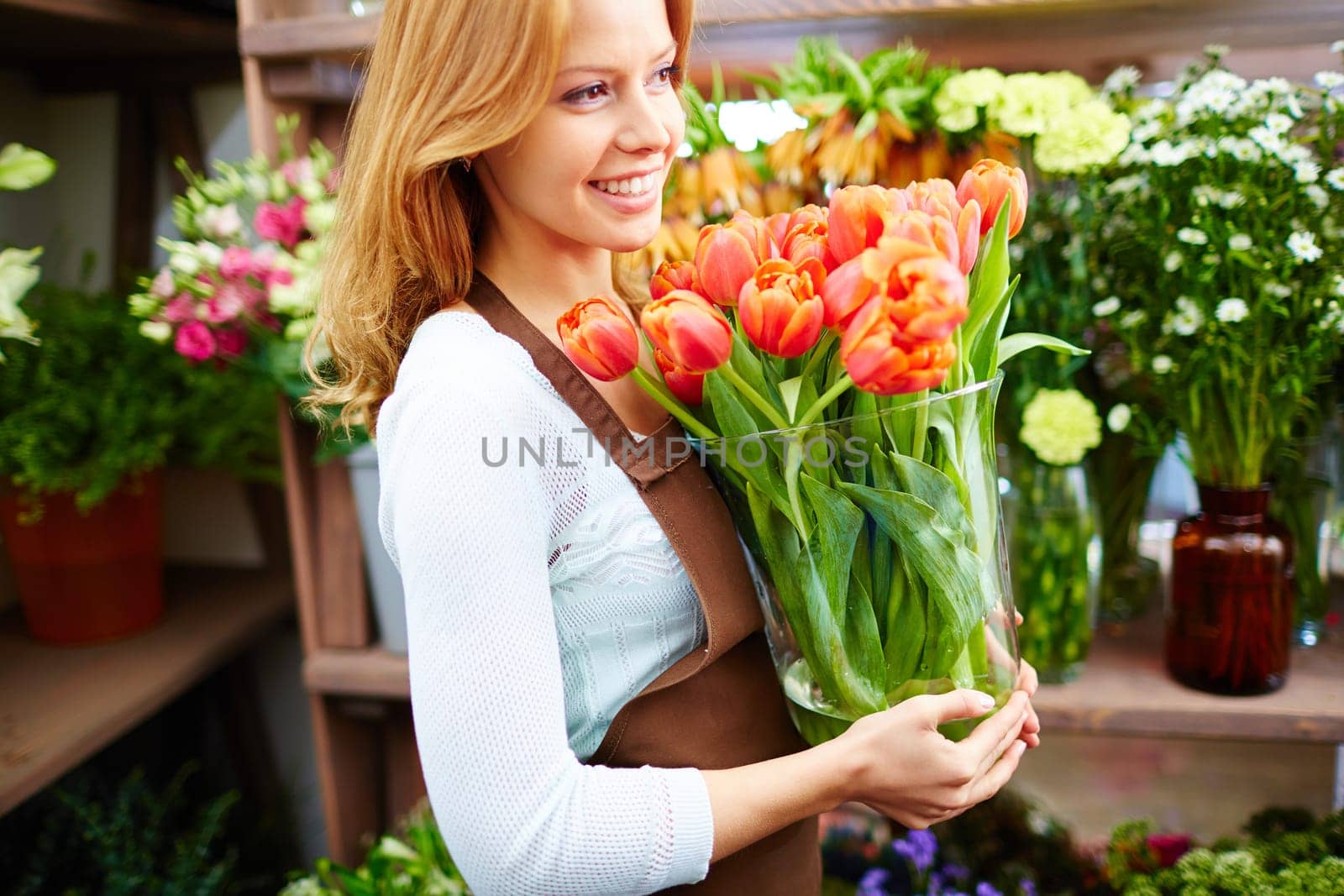 Young florist or gardener holding red tulips in glassware