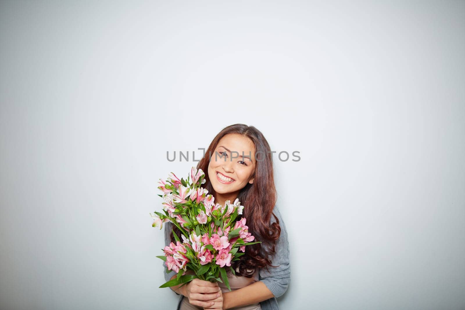Cheerful female with bunch of pink flowers looking at camera