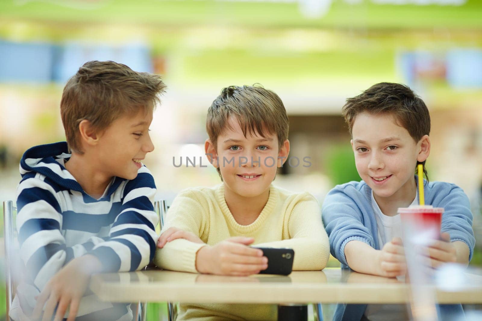 Portrait of three schoolboys sitting at table and looking at camera