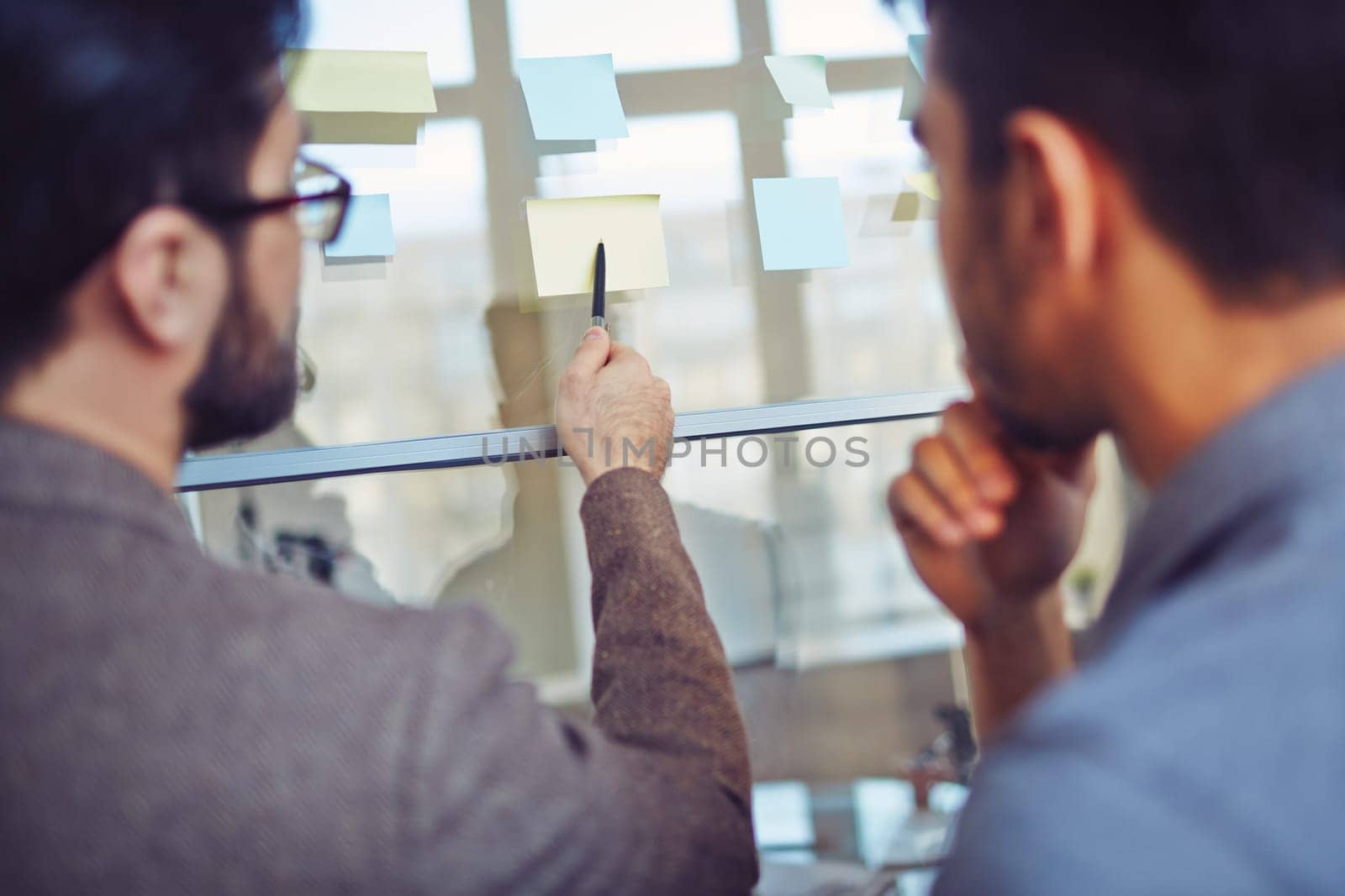 Businessman pointing at notepaper while explaining his idea to colleague