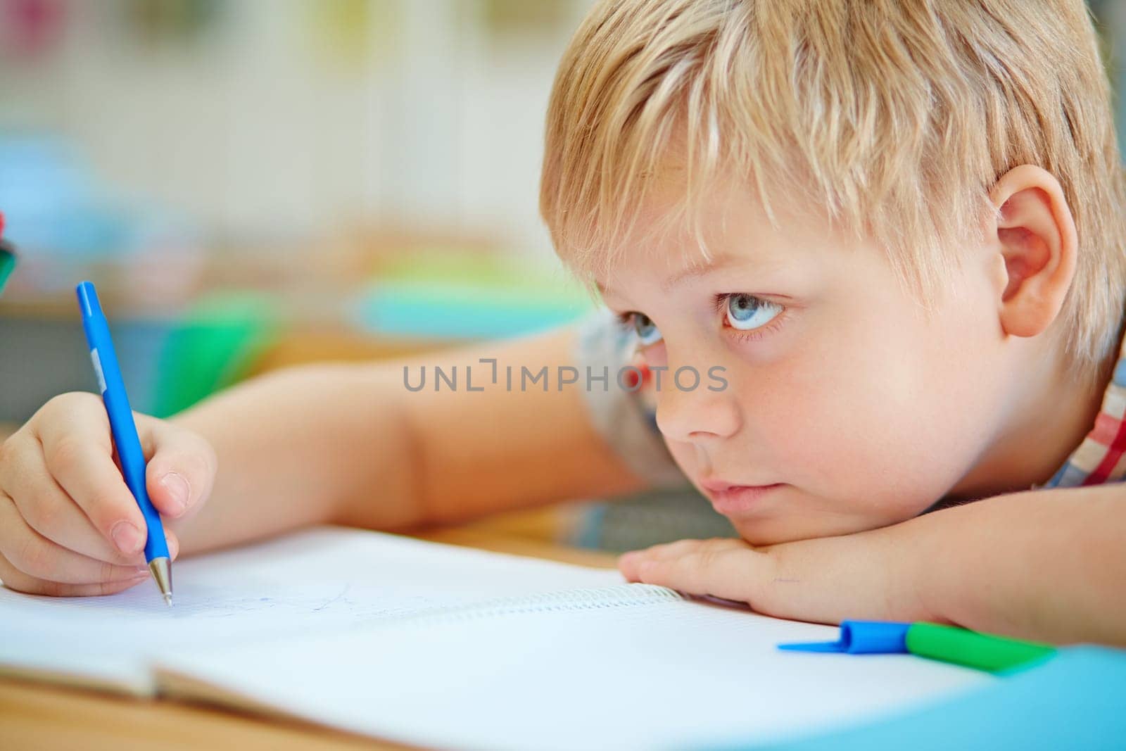 Little learner writing in copybook at lesson