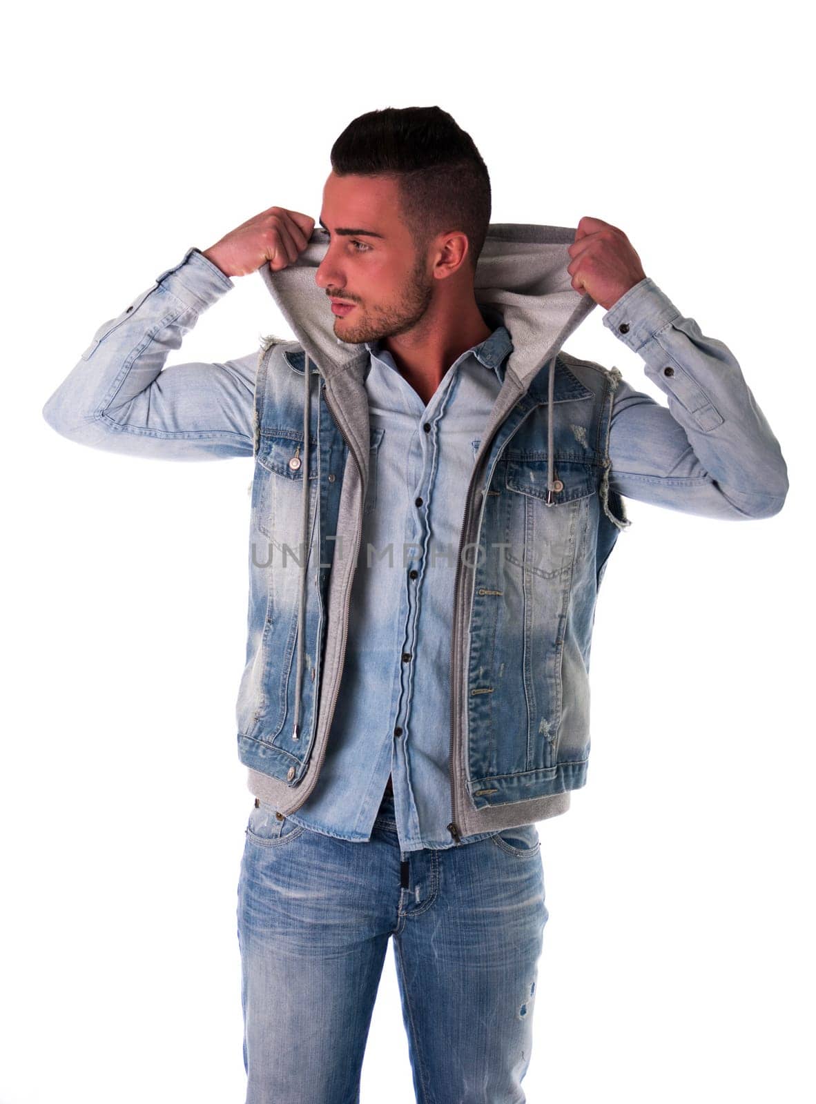 Handsome young man in hoodie, denim vest and jeans, isolated on white