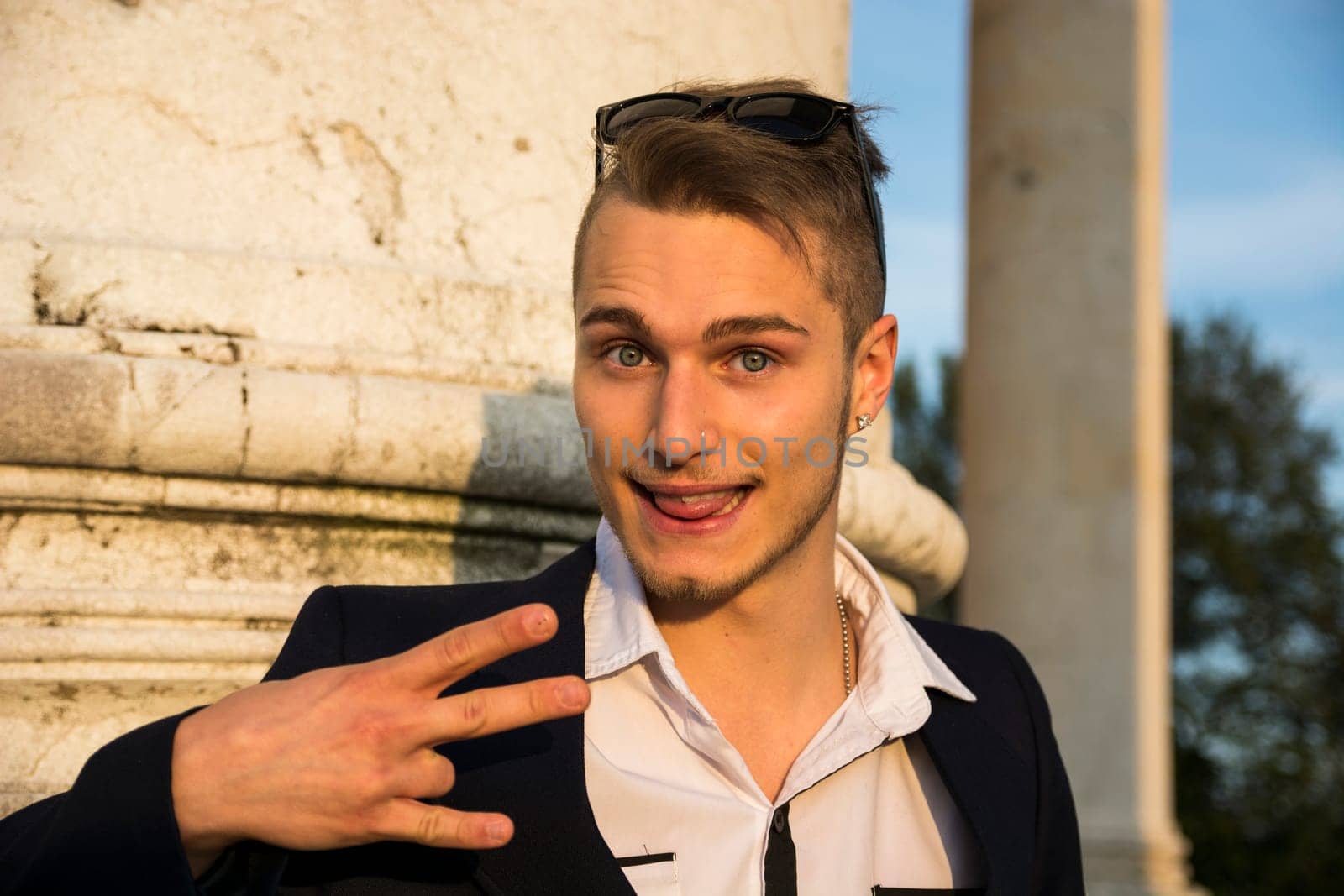 Blond young man with cute, funny expression. Outdoor shot at sundown