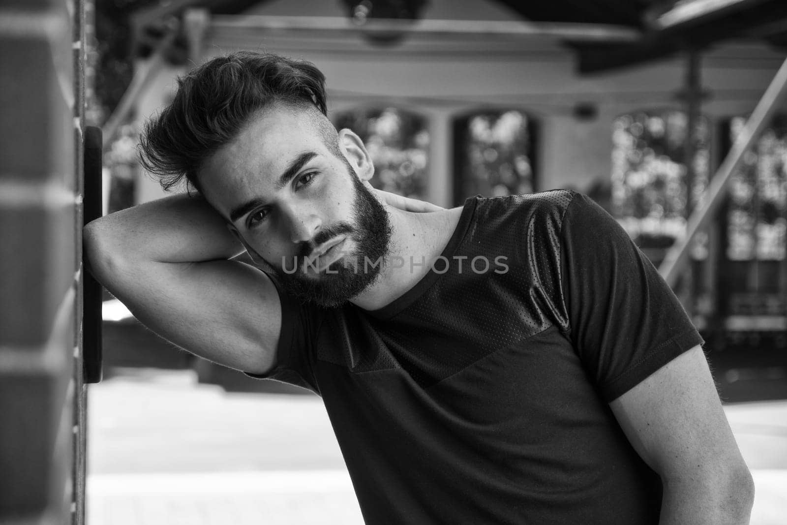 Handsome young man with beard outdoor looking at camera. Black and white shot
