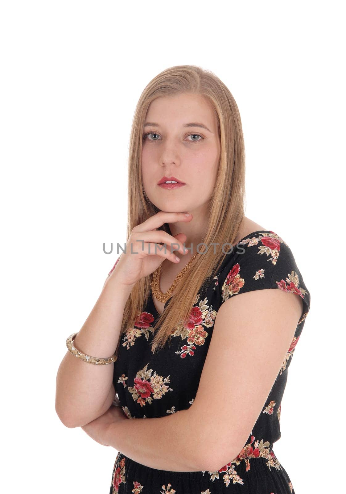A closeup image of a gorgeous blond woman standing in a dress with.one hand on her chin, isolated for white background.