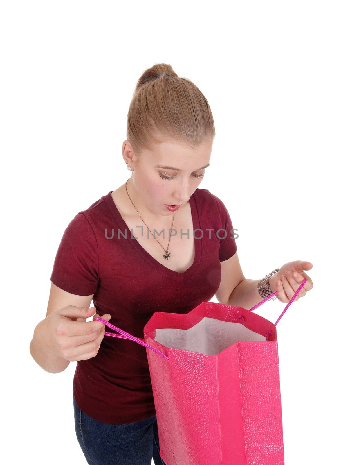 A lovely blond woman in a burgundy sweater holding open her.empty shopping bag, isolated for white background.