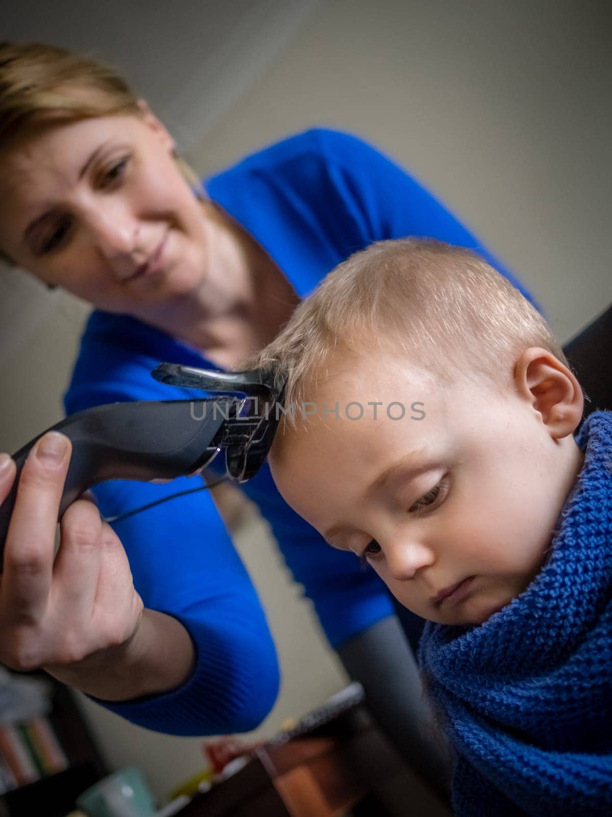Mother cutting hair of her little son