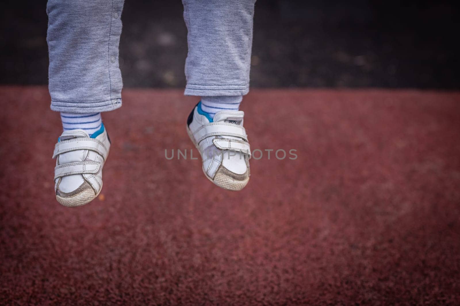 Little boys feet hanging in the air while his is having fun on a swing