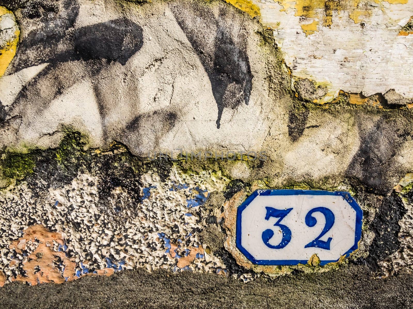 Old door plaque with the number 32 on a wall of an old home