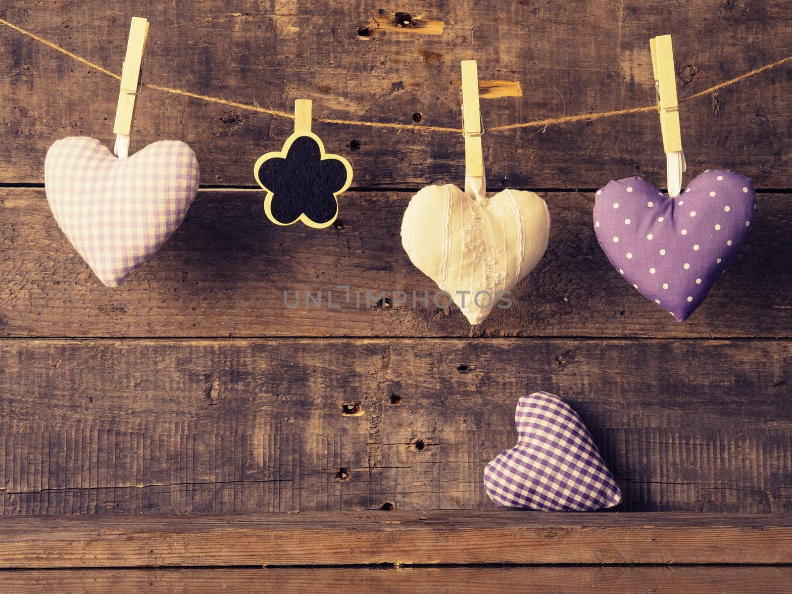 Three fabric heart shapes with a small flower shaped chalkboard on a wooden wall, Valentines Day or Mothers Day concept