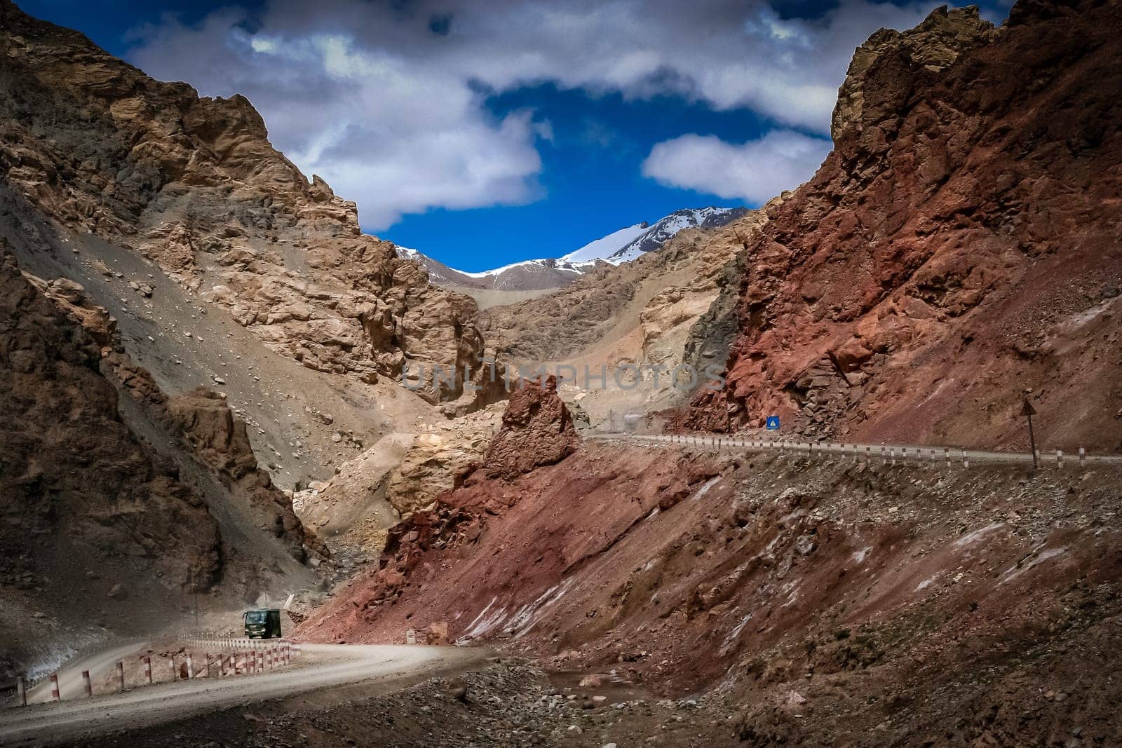 Chinese bus moving slowly uphill on a mountain road through the Western Tibet, China